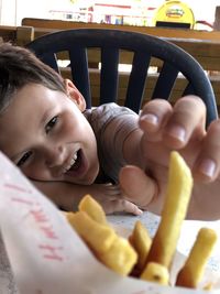 Close-up of boy holding french fries in restaurant