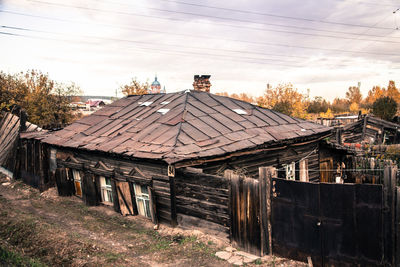 Old house on field by building against sky