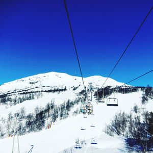 Overhead cable car over snowcapped mountains against clear blue sky