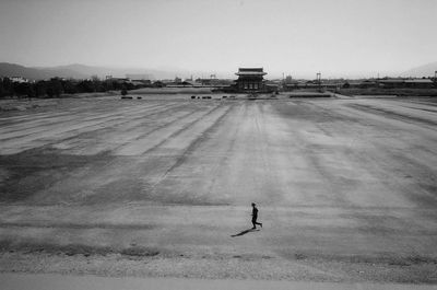 Man standing on airport runway against clear sky