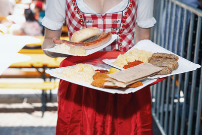 In traditional costume, waitress serving variety of authentic german food at outdoor festival
