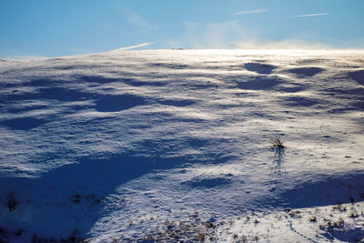 Scenic view of snow covered land against sky