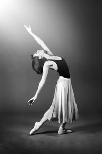 Full length of woman dancing against gray background