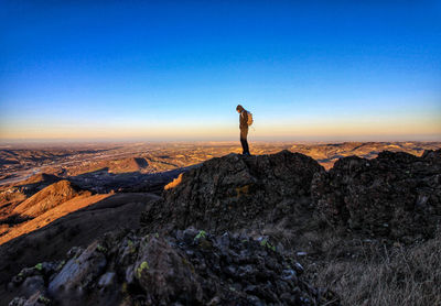 Man standing on mountain against blue sky during sunset