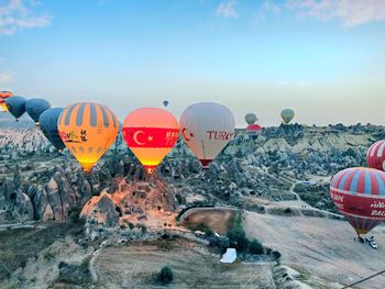 Hot air balloons flying over rocks against sky