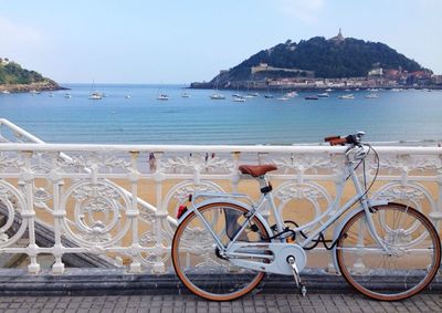 Bicycle parked on footbridge against sea