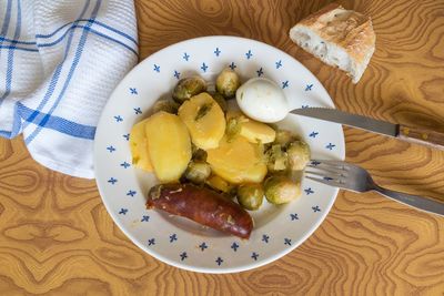 Potatoes, brussels sprouts, egg and chorizo cooked in a plate on a wooden table