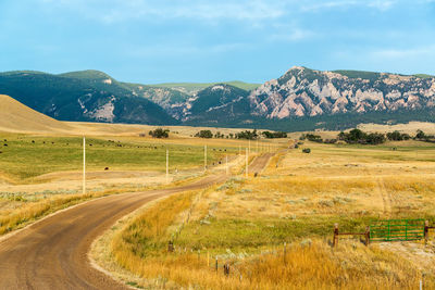 Scenic view of road by mountains against sky