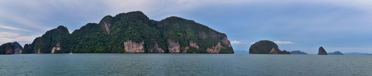 Panoramic view of rocks by sea against sky