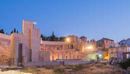 Illuminated buildings against clear blue sky at dusk