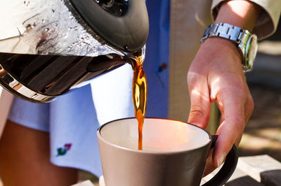 Midsection of man pouring coffee into cup