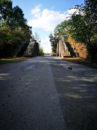 Road amidst trees in city against sky