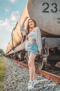 Portrait of smiling young woman standing on railroad track