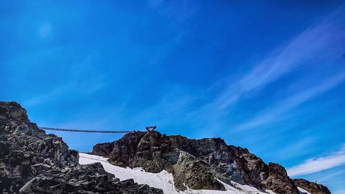 Low angle view of snowcapped mountain against blue sky