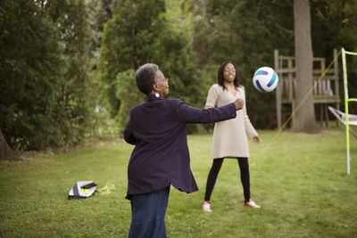 Senior woman and granddaughter playing with ball in backyard