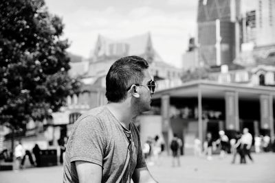 Man wearing sunglasses looking away during sunny day in city