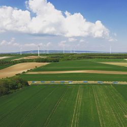 High angle view of agricultural fields against cloudy sky