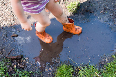 Low section of girl standing in puddle on ground