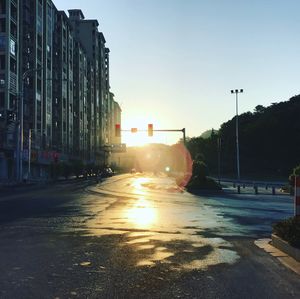 Road by city against clear sky during sunset