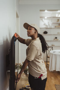 Side view of female technician analyzing level on television set at home