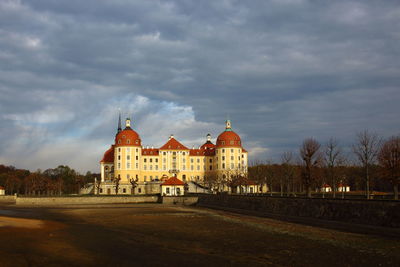 Buildings in city against cloudy sky