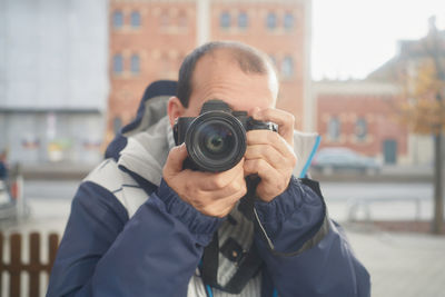 A man takes a picture in front of a mirror on the street in winter