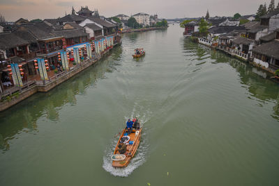 High angle view of people on boat in river amidst houses