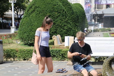 Full length of friends sitting on mobile phone