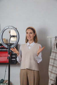 Woman millennial fashion stylist records fashion video on smartphone with ring lamp