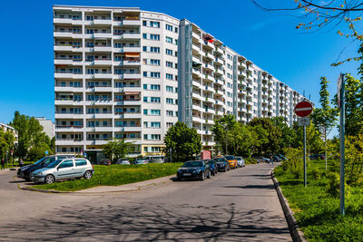 Cars on road by buildings against sky in city