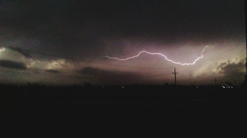 Lightning in sky over silhouette field