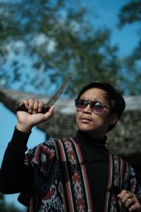 Portrait of young man holding sunglasses