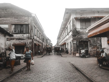 People walking on street amidst buildings in city