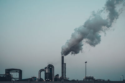 Smoke emitting from factory against clear sky