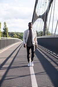 Full length of young man standing on footbridge