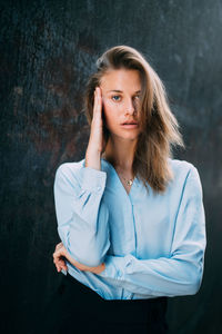 Portrait of young woman standing against wall