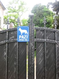 Information sign by fence against trees