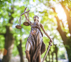 Low angle view of lady justice statue against trees