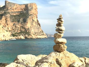 Rock formation by sea against sky