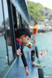 Boy peeking from boat window in sea