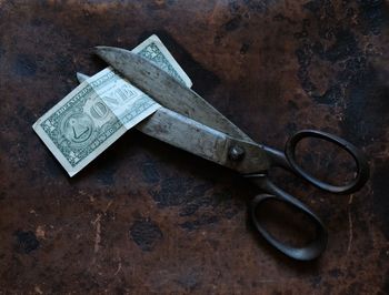 High angle view of scissor with paper currency on table