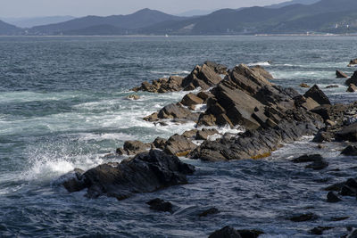 Rocks on shore by sea against sky