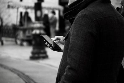 Midsection of man using mobile phone in city