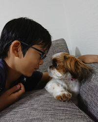 Close-up of boy and dog face to face on sofa