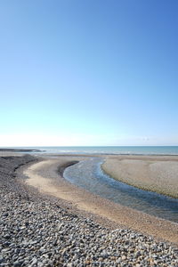 Surface level of beach against clear blue sky