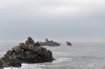 Scenic view of rocks in sea against sky