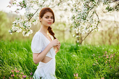 Portrait of smiling young woman standing on field