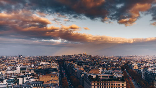 Aerial view of cityscape against cloudy sky