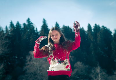 Smiling girl throwing snow while standing outdoors