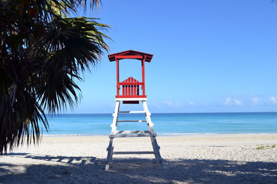 Lifeguard hut on beach against clear blue sky